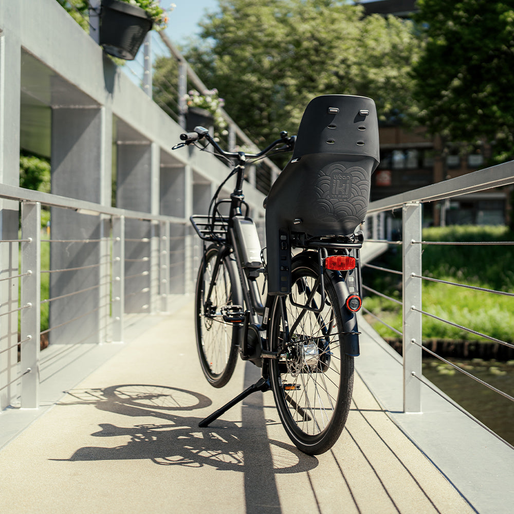 Urban Iki achterzitje U-me MIK HD voor fiets, met comfortabele zit en veiligheidsriemen, bevestigd op de achterdrager van de fiets.