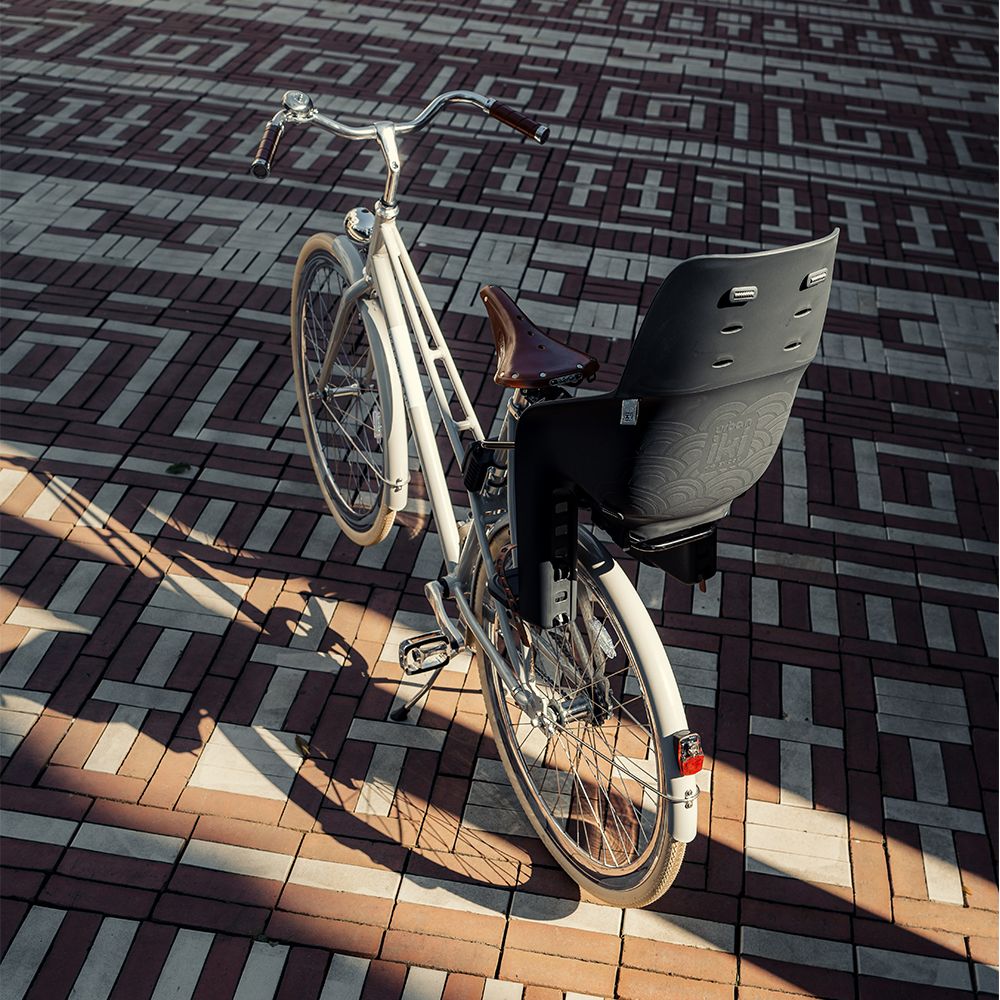 Urban Iki achterzitje U-me MIK HD voor fiets, bevestigd op de achterdrager, met veiligheidsriem en zwart ontwerp.