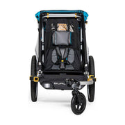 Burley D'lite X enkele kinderfietskar in sagegroen en grafietgrijs, met comfortabele zitplaatsen en veiligheidsriemen.