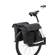 Nieuwe Looxs Leeds Double MIK 2.0 dubbele fietstas met 38 liter capaciteit, zwart en waterbestendig, bevestigd aan fietsdrager.